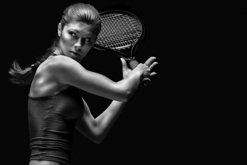 Female tennis player with racket ready to hit a tennis ball.